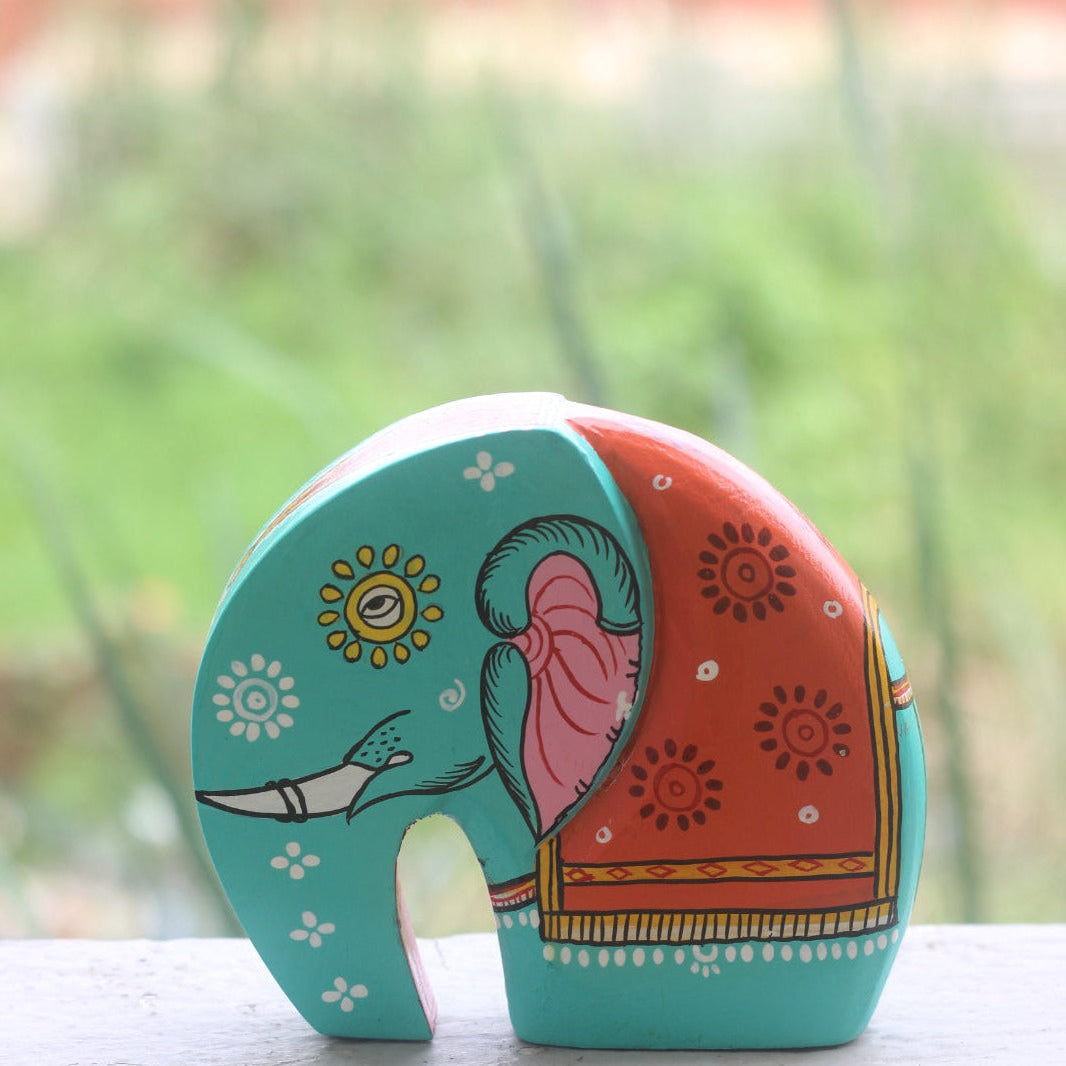 Colorful elephant-shaped object with patterns on a white surface with a blurred green background